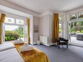 A bedroom with a bed and windows leading to outdoor seating at tbc