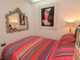 A bedroom with a bed, lamp, mirror, and wall art at Hillsover in Saltburn-by-the-Sea