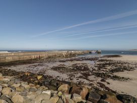 A view of a pier at low tide with rocks and seaweed at Cabin 3 Cnoc na Naomh in Gortahawk