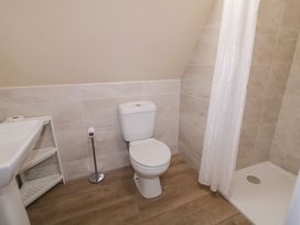 A bathroom with a toilet, sink, shower, and storage shelf at Cabin 4 Doire Chonair in Gortahawk