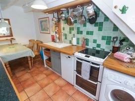 A kitchen with a stove and dining table at St. Dominic Cottage in St. Ives