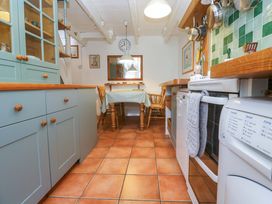 A kitchen with cabinets and a table at St. Dominic Cottage in St. Ives