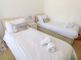 A bedroom with two beds and a side table at St. Dominic Cottage in St. Ives