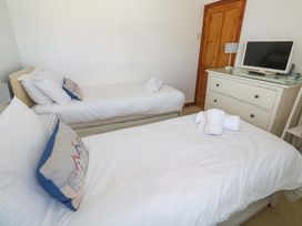 A bedroom with twin beds and dresser at St. Dominic Cottage in St. Ives