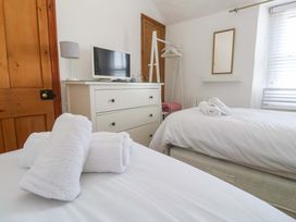 A bedroom with a bed, dresser, television and towels at St. Dominic Cottage in St. Ives