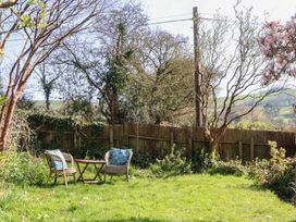 A garden with chairs and a table at Upper Frogpool Cottage in Crediton