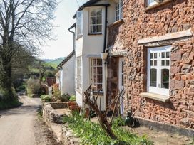 A stone building with windows and plants along a pathway at Upper Frogpool Cottage in Crediton