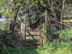 A gate with a sign and trees at Upper Frogpool Cottage in Crediton