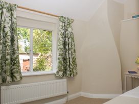 A bedroom with a window and curtains at Upper Frogpool Cottage in Crediton