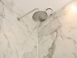 A shower head mounted on a marble wall at Upper Frogpool Cottage in Crediton