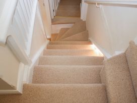 A staircase with carpet leading to a doorway at Upper Frogpool Cottage in Crediton