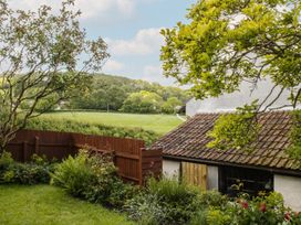 A garden with grass, trees, and a view of a field at Upper Frogpool Cottage in Crediton