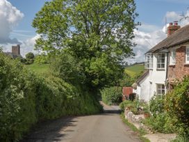 A road with cottages and a church tower at Upper Frogpool Cottage in Crediton