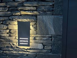 A stone wall with a lighting fixture and sign at Midways Windermere