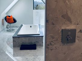 A bathroom with a bathtub and a chair at Midways in Bowness-On-Windermere