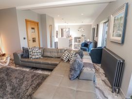 A living room with a sofa and kitchen area at Midways in Bowness-On-Windermere