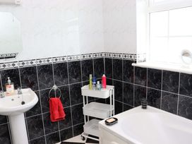 A bathroom featuring a wash basin, bathtub, and storage cart at BREAGHMORE