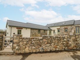 An outdoor view of a stone house and wall at Barley Cottage in Oxwich