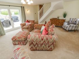 A living room with seating furniture and stairs at Barley Cottage in Oxwich