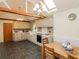A kitchen with cabinets and a dining table at Barley Cottage in Oxwich