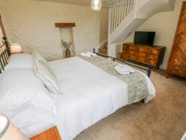 A bedroom with a bed and TV at Barley Cottage in Oxwich