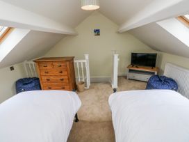 A bedroom with two beds and a television at Barley Cottage in Oxwich