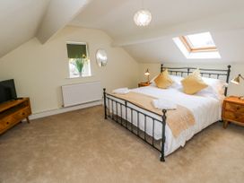 A bedroom with a bed and TV at Barley Cottage in Oxwich