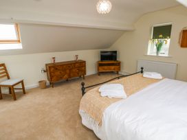 A bedroom with a bed, chair, and television at Barley Cottage in Oxwich