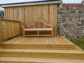 A bench on a wooden deck at Barley Cottage in Oxwich