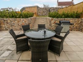 A patio with a table and chairs and a grill at Barley Cottage in Oxwich