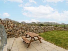 A garden with a picnic table and stone walls at Barley Cottage in Oxwich