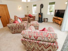 A living room with sofas and a wood stove at Barley Cottage in Oxwich