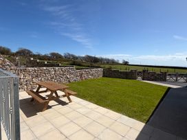 A garden with a picnic table and stone wall at Barley Cottage in Oxwich