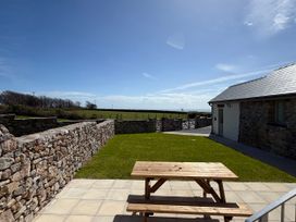 An outdoor area with a table and stone walls at Barley Cottage in Oxwich