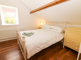 A bedroom with a bed, lamp, and window at Artist’s Cottage in Cashel, County Tipperary