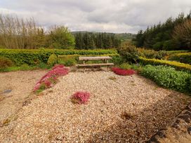 A garden area with a picnic table surrounded by gravel and flowers at Artist’s Cottage in Cashel, County Tipperary