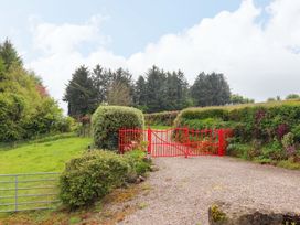 A red gate with gravel path and greenery at Artist’s Cottage in Cashel, County Tipperary