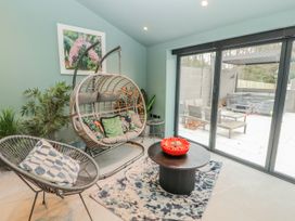A conservatory with a hanging chair and table at Bounty Boutique on the Lakes in Bowness-On-Windermere