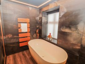 A bathroom with a bathtub and towel rack at Bounty Boutique on the Lakes in Bowness-On-Windermere
