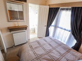 A bedroom with a bed and a door to the bathroom at 13 The Lakes in Mablethorpe