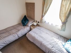 A bedroom with two beds and a window at 13 The Lakes in Mablethorpe