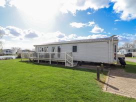 A mobile home with a deck and grassy area at 13 The Lakes Mablethorpe
