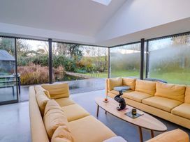 A snug area with a yellow sofa and a view of the garden at Bredy Cottages in Burton Bradstock