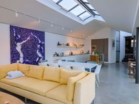 A living room with a yellow sofa and kitchen counter at Bredy Cottages in Burton Bradstock