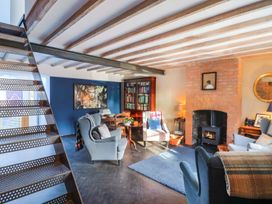 A living room with a staircase and bookshelf at Bredy Cottages in Burton Bradstock