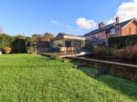 A garden with a modern house and pond at Bredy Cottages in Burton Bradstock