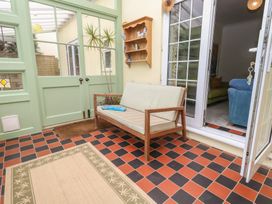 A conservatory with a sofa and a shelf at Millmead House in Portesham