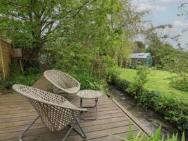 A garden with two chairs and a table near a stream at Millmead House Portesham