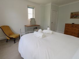 A bedroom with a bed, chair, dresser, and mirror at Millmead House in Portesham