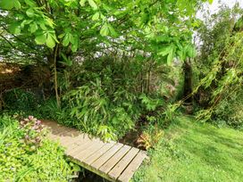 A garden with a wooden bridge and green plants at Millmead House in Portesham